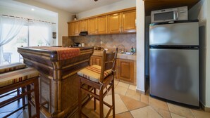 A kitchen with wooden cabinets, a stainless steel refrigerator, a microwave, and a ceiling fan.