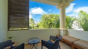 A balcony with a table, two chairs, a bench, and a potted plant.