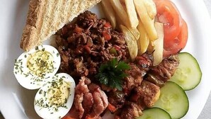 Un plato con carne a la parrilla, rodajas de tomate, rebanadas de pepino, zanahorias, huevos cocidos y pan tostado.
