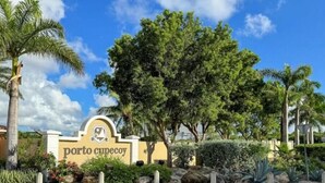 A sign with "porto cepesco" written on it, surrounded by greenery and palm trees.