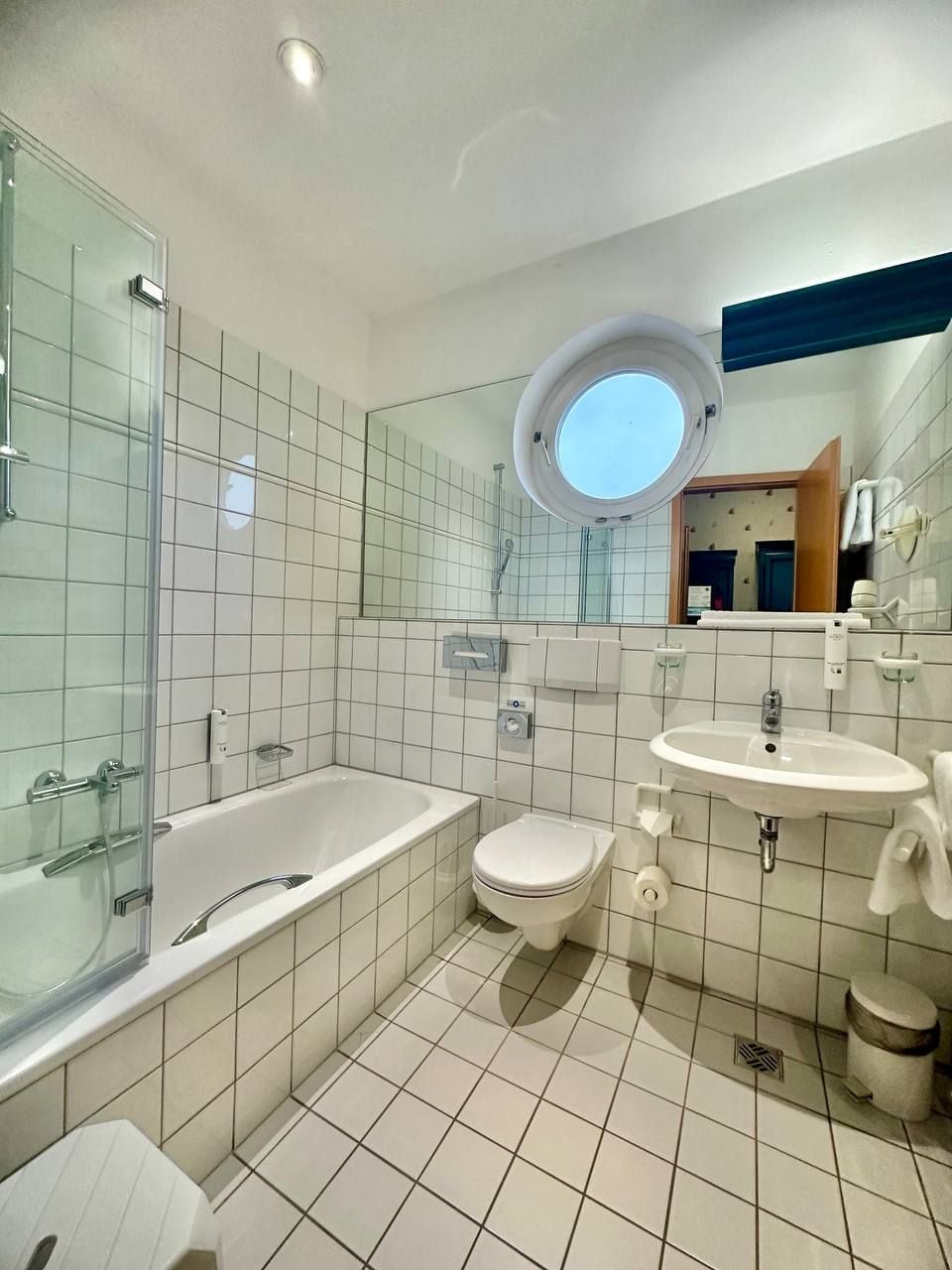 Een moderne badkamer met een douche met glazen wand, een bad, toilet en wastafel.