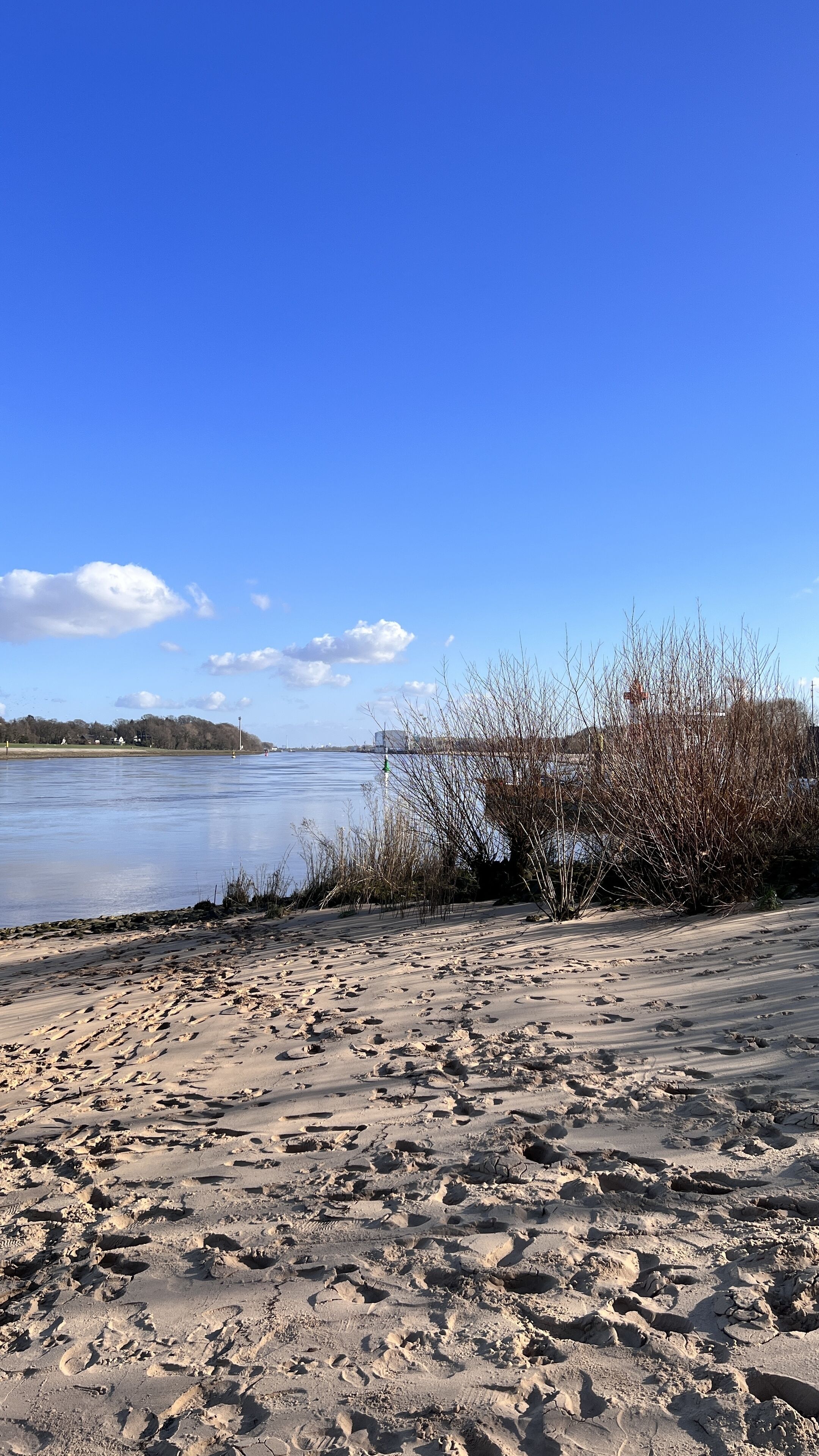 A sandy beach with footprints leading to a river.