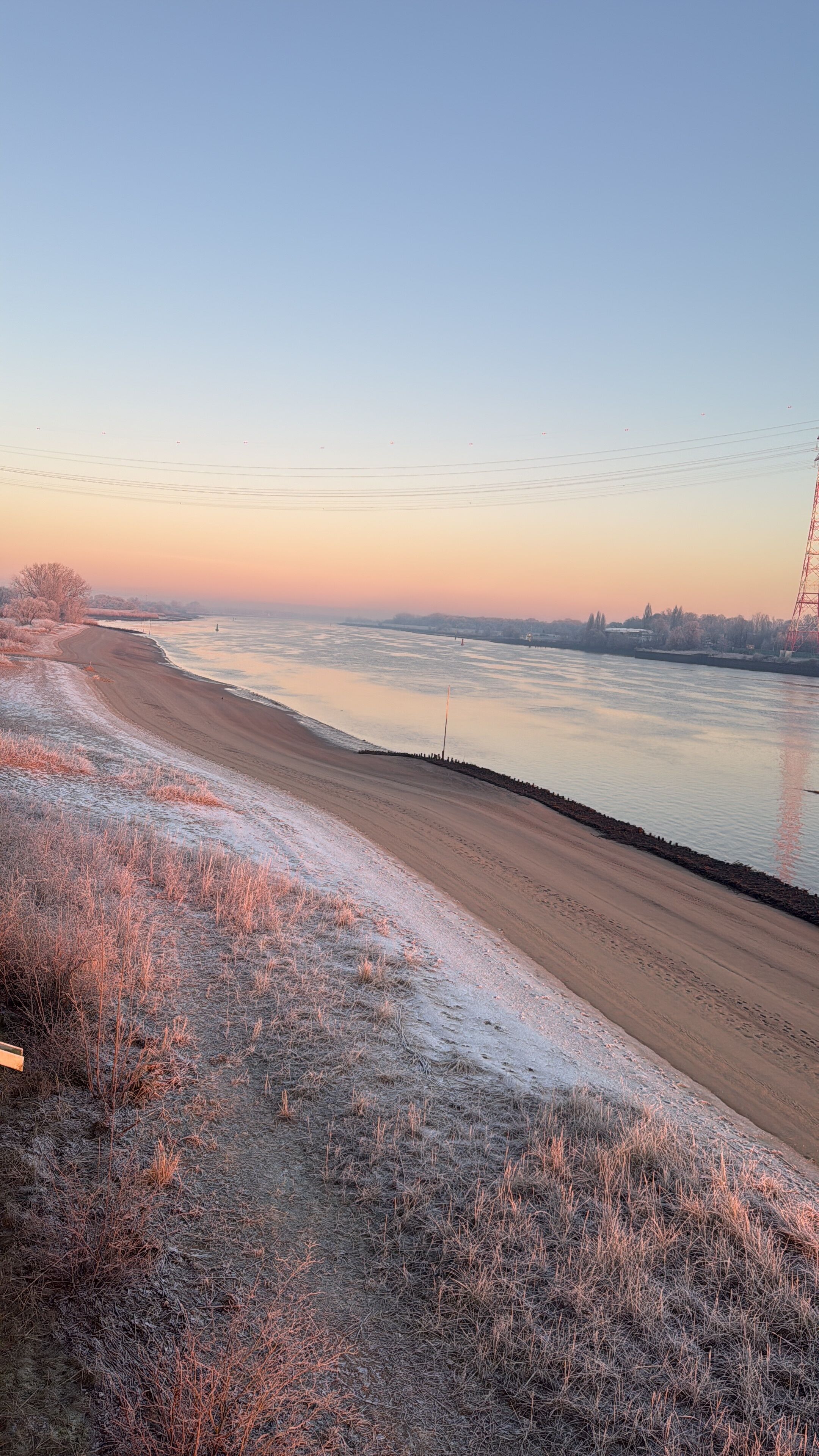 A riverside view with a sandy beach and sparse vegetation.