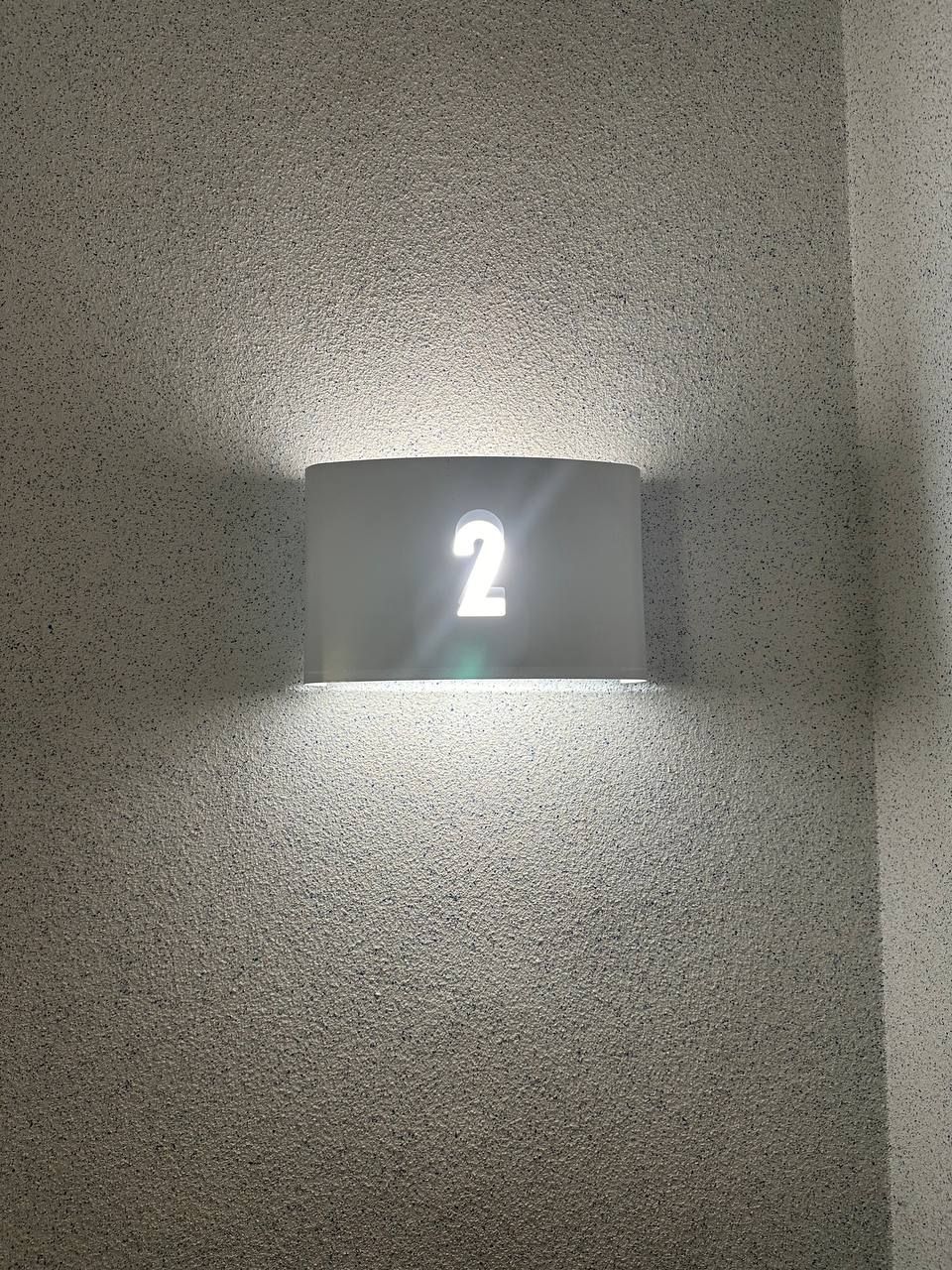 A wall-mounted light fixture with the number '2' illuminated.