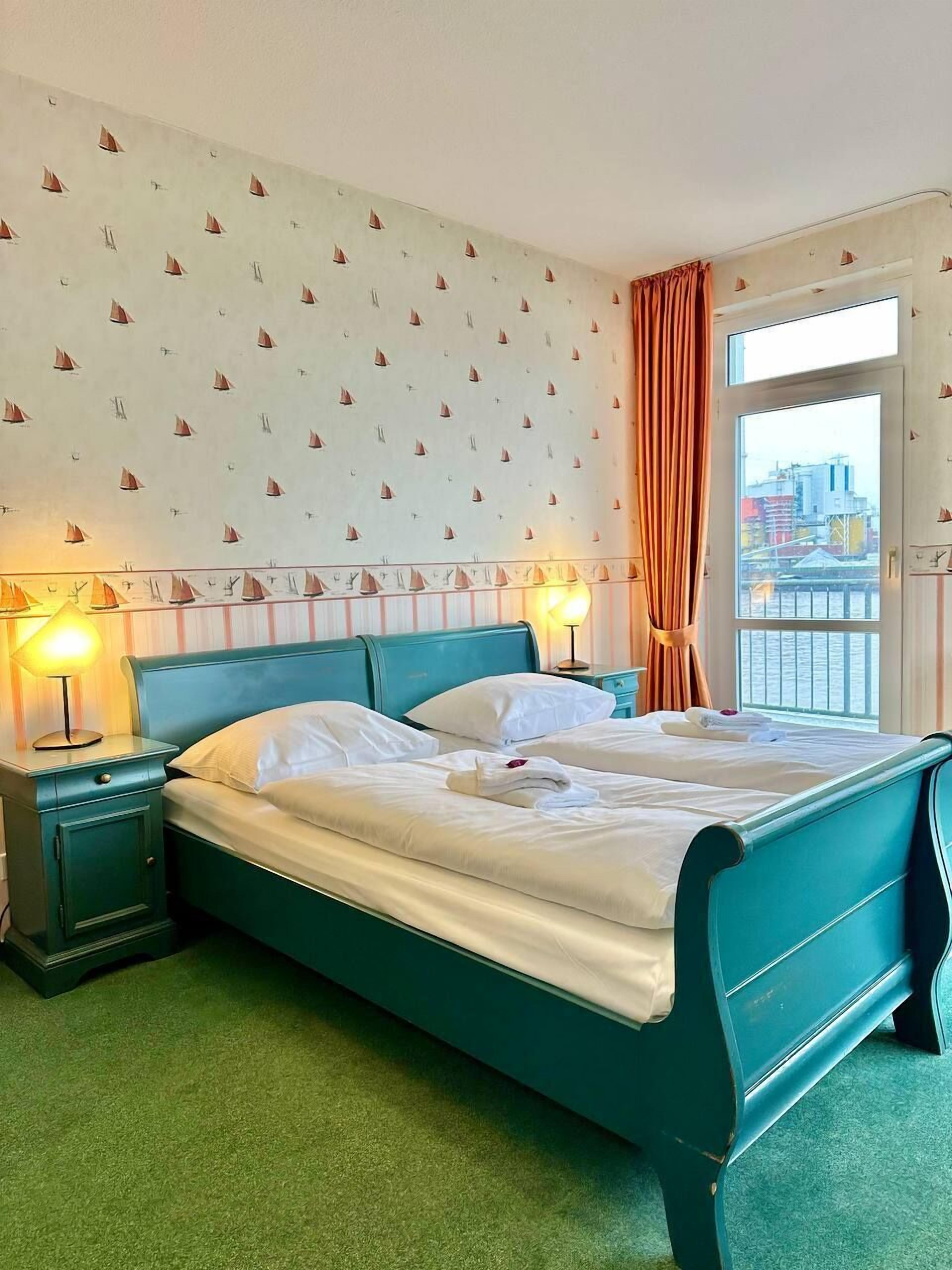 A hotel room with a large bed, two bedside tables, a window with curtains, and a city view.