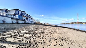 A beach with footprints leading to a building with large windows and a sign that reads "Weselke Restaurant". - Gästehaus Weserblick (Berne)