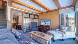 A spacious living room with a large window, a fireplace, and a television. - Snowflake on Copper Mountain 3 Bedroom Ski In / Ski Out! (Frisco)