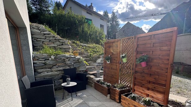 Un espace patio agrémenté d’un mur en pierre, d’une clôture en bois et d’un coin salon avec une table et des chaises.