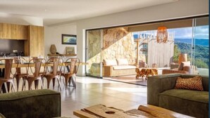 A modern living room with a large glass door leading to a balcony with a scenic view.