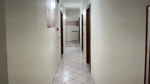 A hallway with white walls, tiled flooring, and doors on both sides. - Hotel Eliseo Napoli (Naples)
