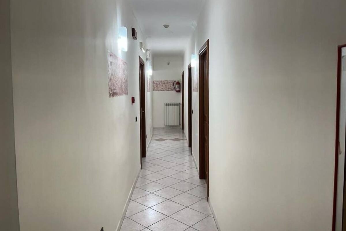 A hallway with white walls, tiled flooring, and doors on both sides.