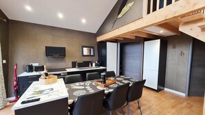 Cozinha moderna com área de refeições, teto de madeira e uma janela grande.