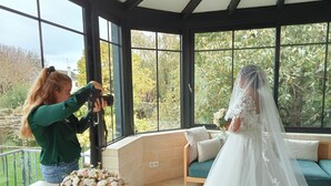 Une pièce dotée de grandes fenêtres, d’un banc en bois et d’une table agrémentée de compositions florales.