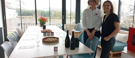 Comedor con mesa dispuesta para dos, una planta en maceta y botellas de vino.