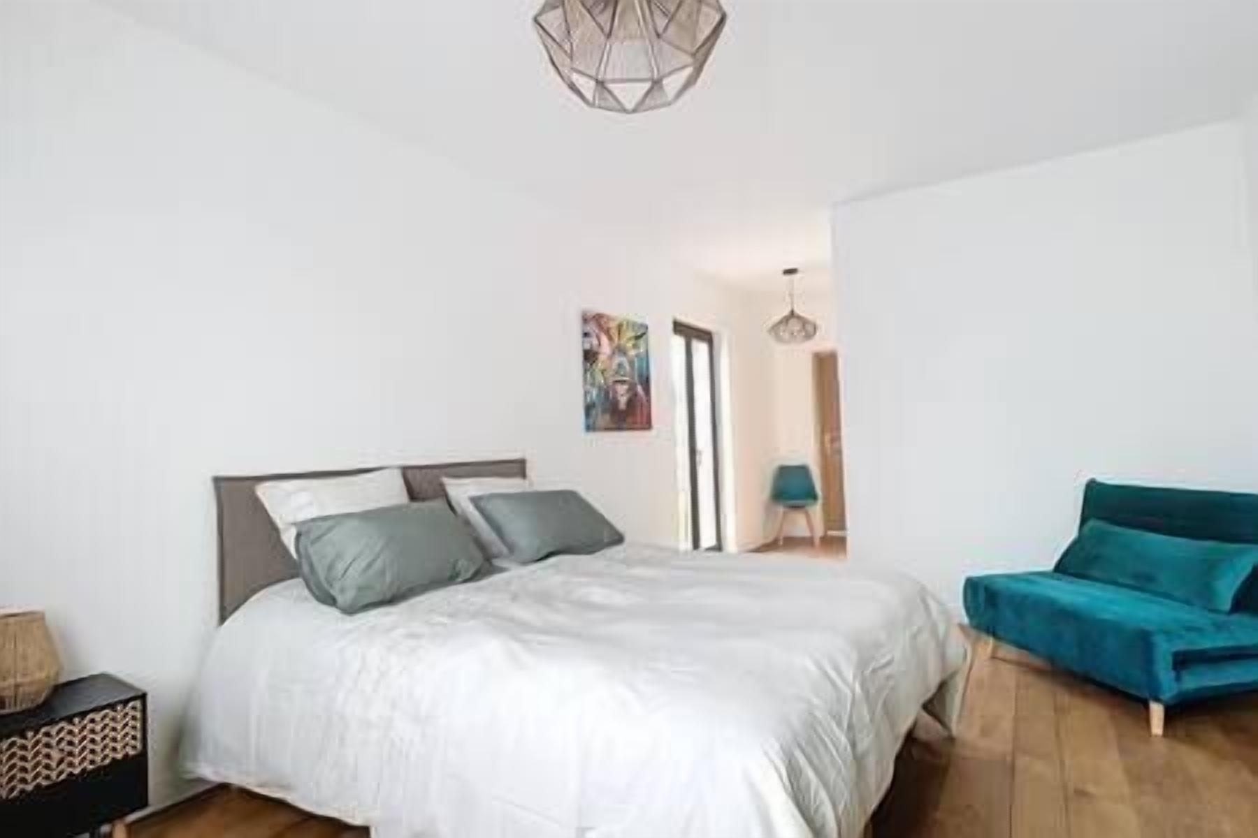 Un dormitorio con cama, una silla y un cuadro en la pared.