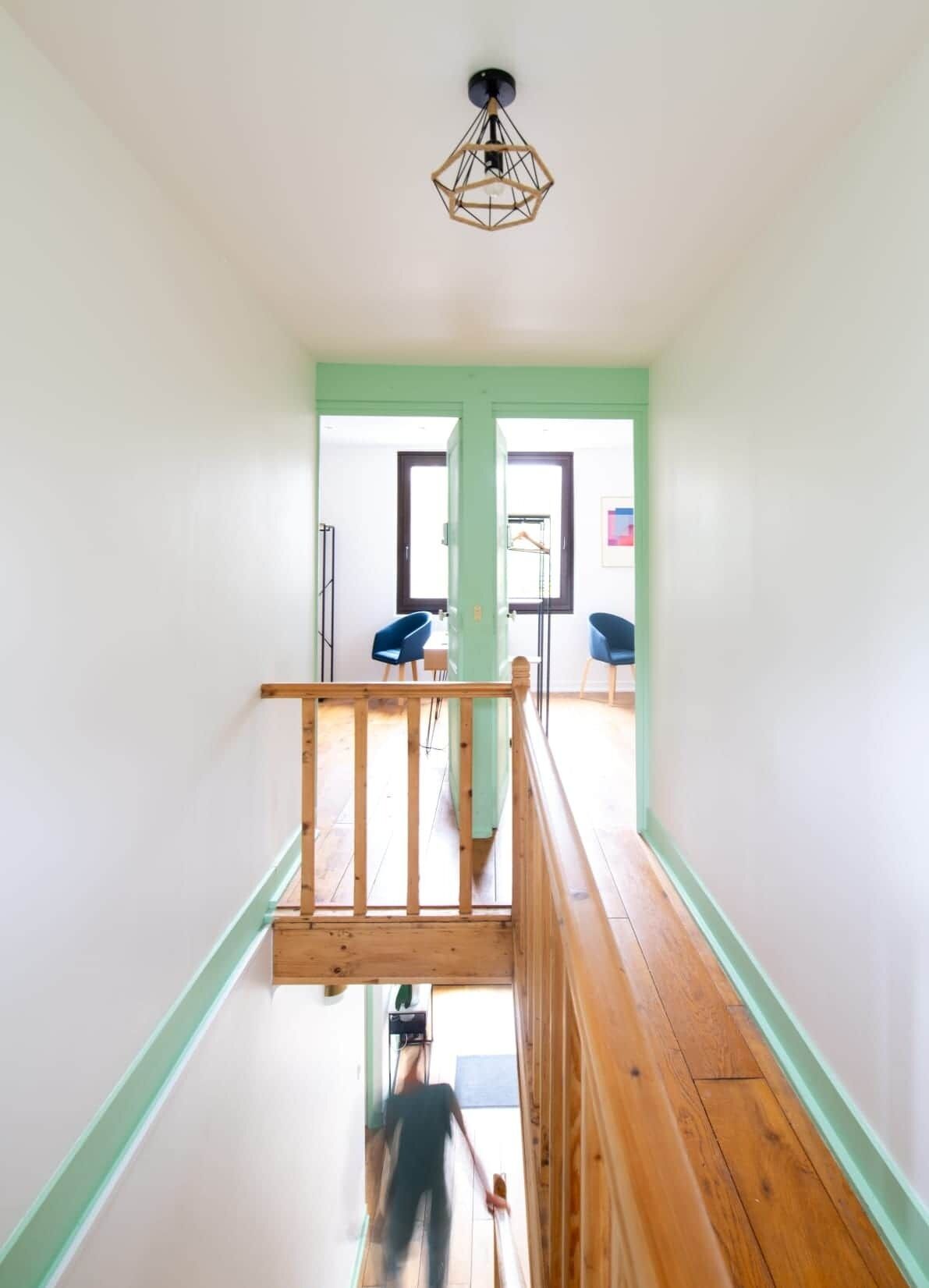 A staircase with a wooden handrail leading to a landing with a view of a room.