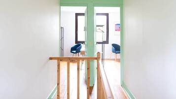 A staircase with a wooden handrail leading to a landing with a view of a room.