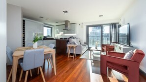 Un apartamento moderno con comedor, cocina, sala de estar y un amplio ventanal con vista a la ciudad.