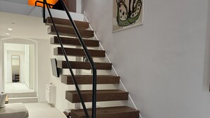 A modern staircase with wooden steps and black railings, leading to a bright hallway. - Old Stone House. Spacious Loft in the heart of the old town a stone's throw from the sea (Bari)