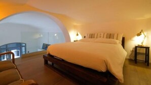 A bedroom with a large bed, a chair, a desk, and a view of a balcony. - Old Stone House. Spacious Loft in the heart of the old town a stone's throw from the sea (Bari)