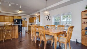 A spacious kitchen with wooden cabinets, a dining table with chairs, and a large window providing natural light.