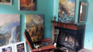 A room with teal walls, a fireplace, and several framed paintings. - Randy's Roost -- Private unit within an artists home/studio and gallery. (Santa Fe)