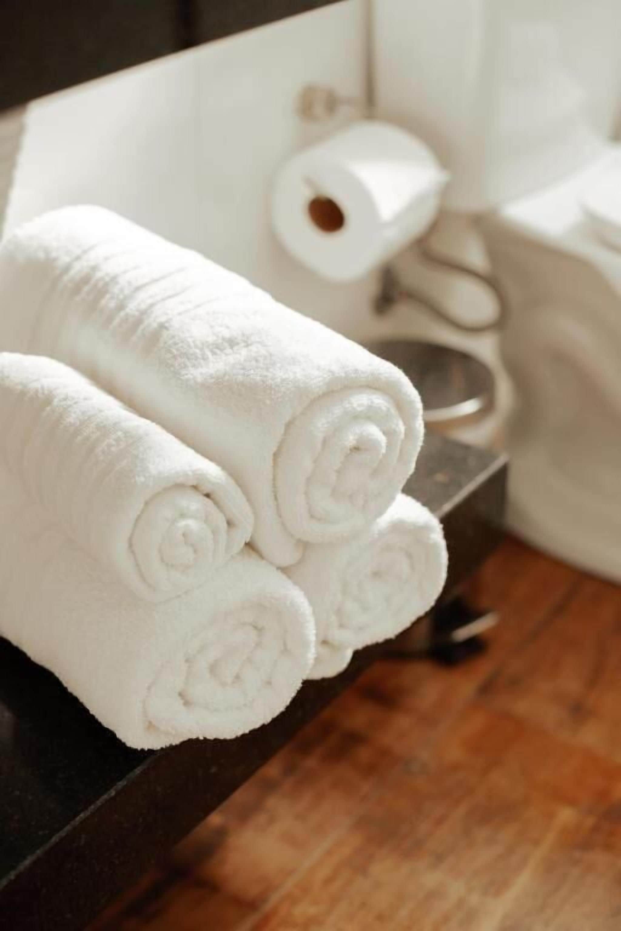 A bathroom with white towels stacked on a dark surface.