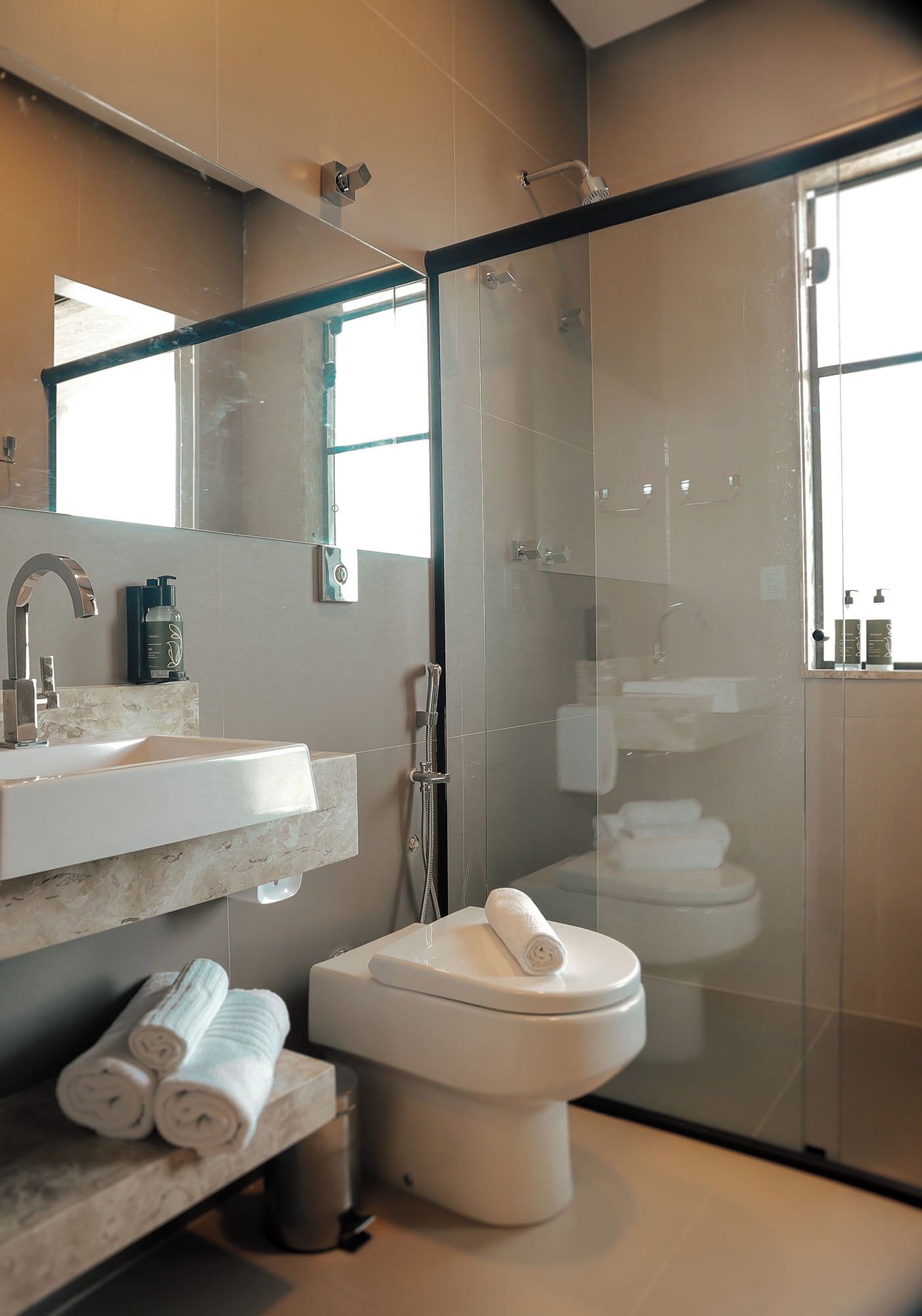 A modern bathroom with a glass-enclosed shower, a white sink, and a toilet.