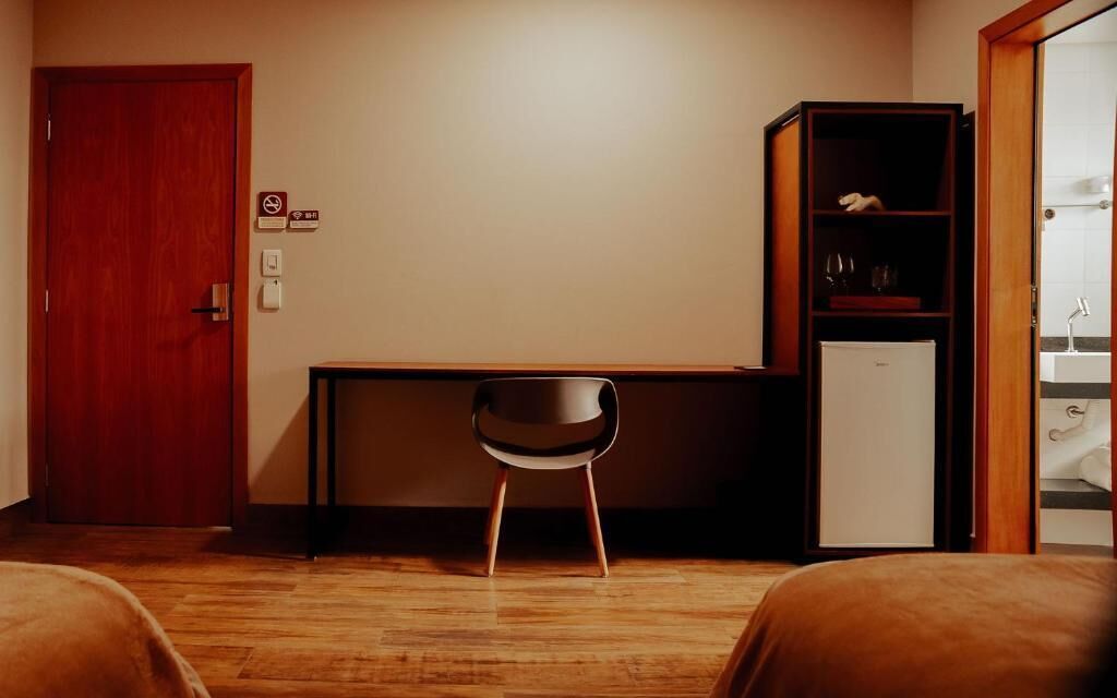 Ein Hotelzimmer mit einem Holztisch, einem Stuhl, einem Kleiderschrank und einem Bett.