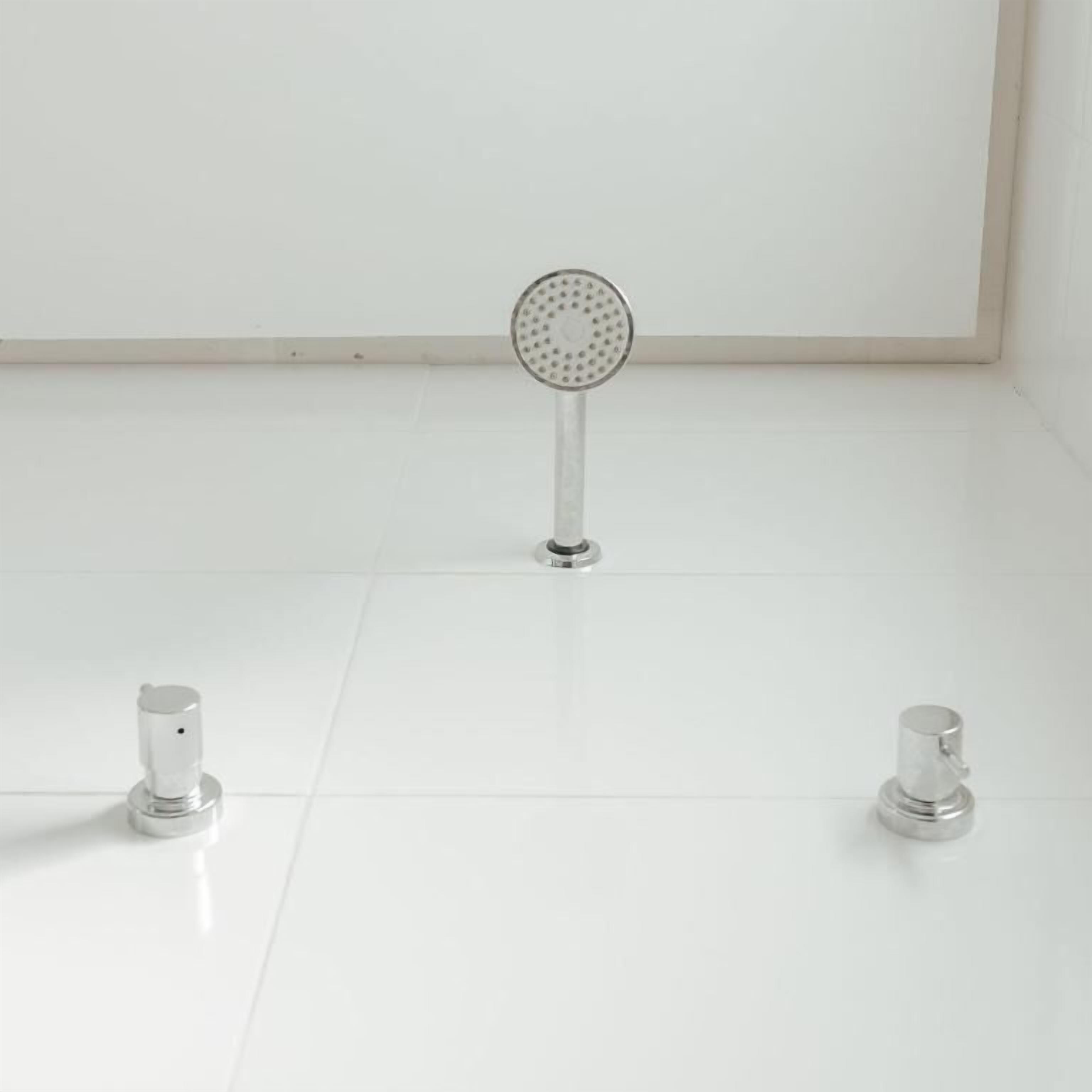 Un baño con piso blanco, un cabezal de ducha y dos grifos.