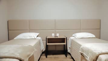 A double room with two beds, a wooden nightstand, and two bedside tables with electrical outlets.