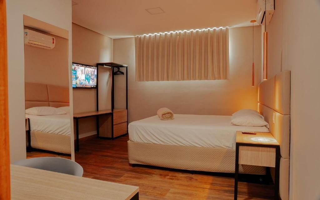 A compact hotel room with a bed, a desk, a TV, and a wardrobe.