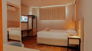 A compact hotel room with a bed, a desk, a TV, and a wardrobe.