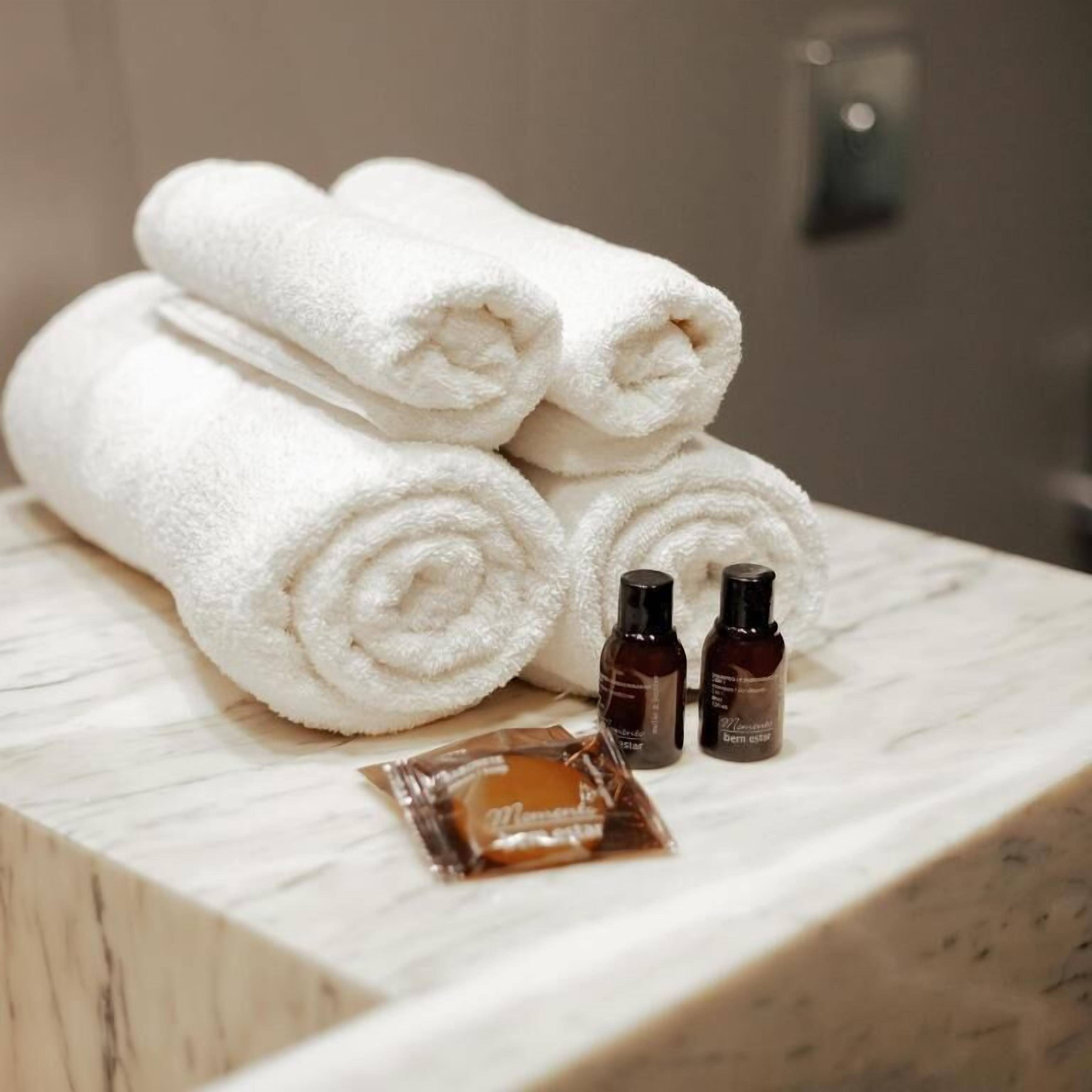 A marble-topped table with neatly rolled white towels, two small brown bottles, and a small brown packet.