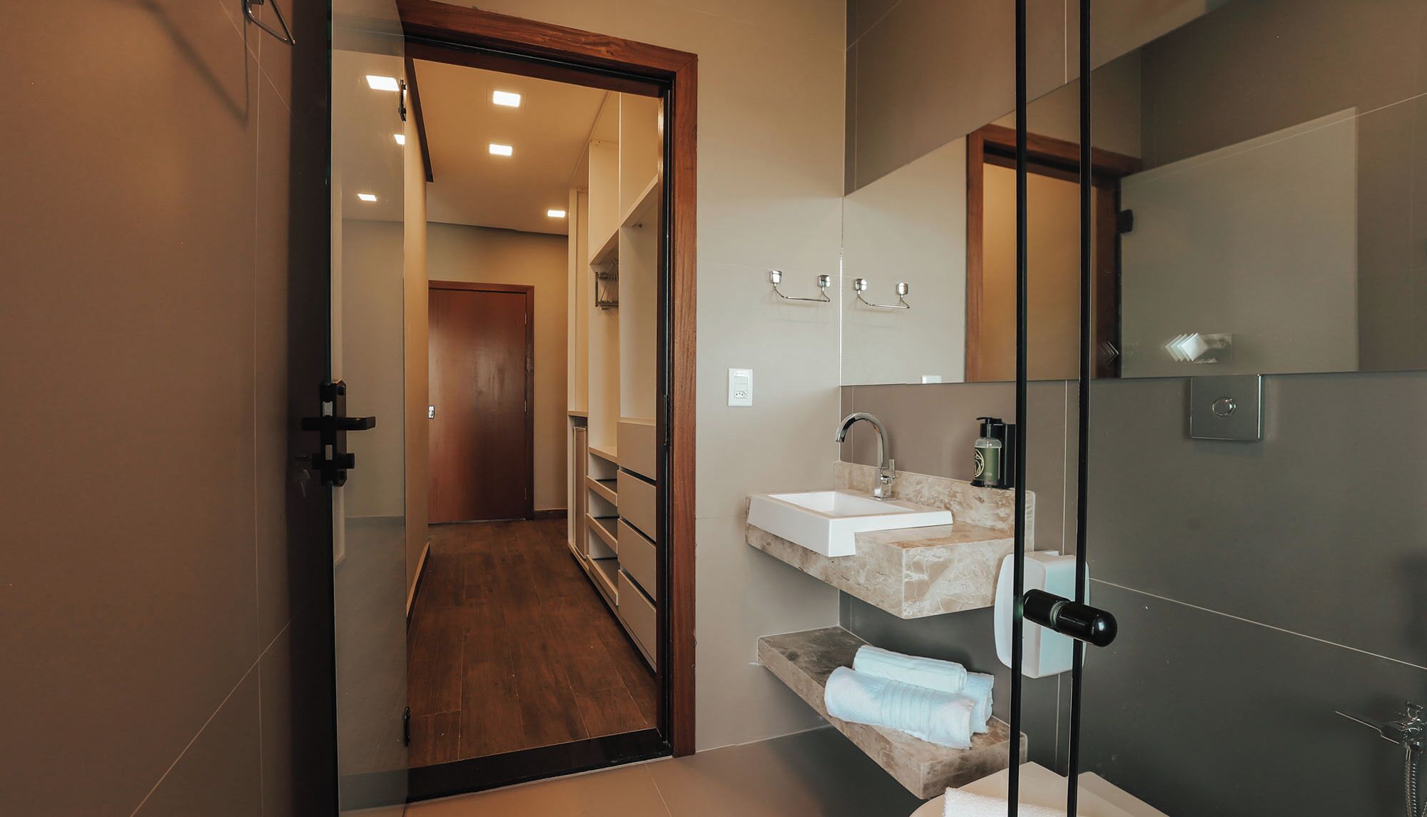 Un baño moderno con cabina de ducha de vidrio, un lavabo con encimera de mármol y un espejo sobre el lavabo.