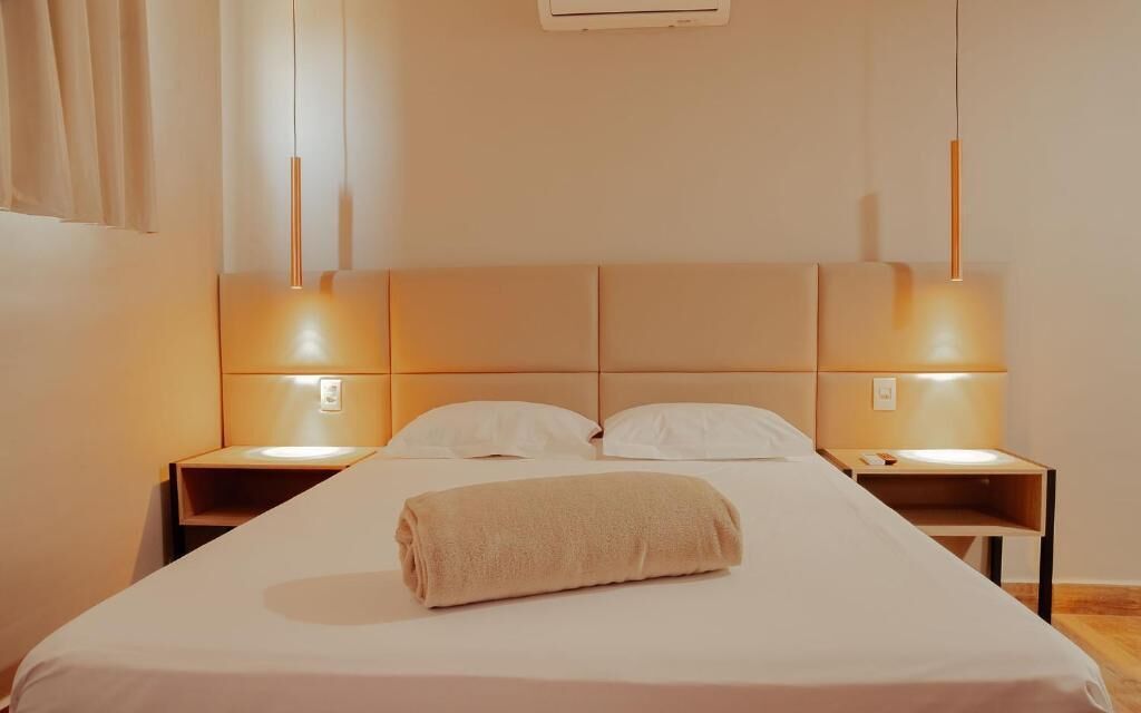 Ein Hotelzimmer mit einem großen Bett, zwei Nachttischen und einem Kopfteil.