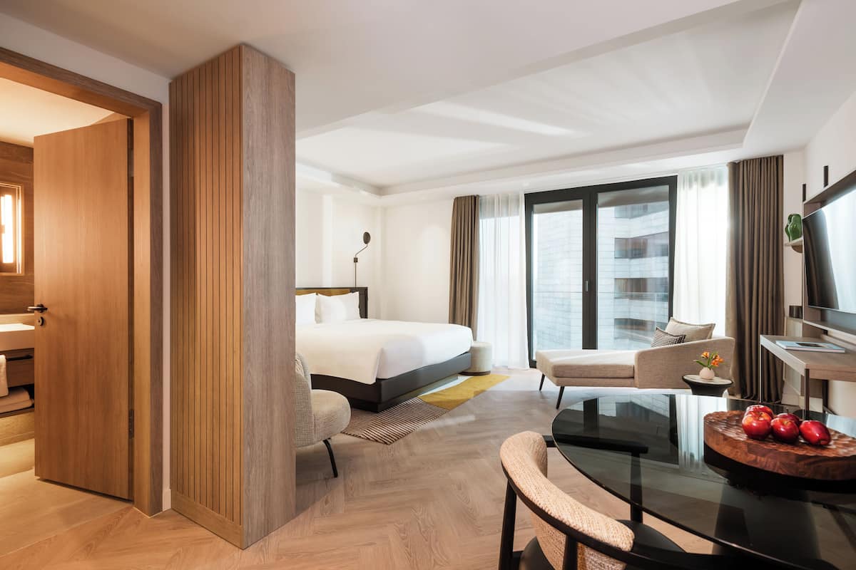 Una habitación de hotel con cama, sofá, escritorio y televisión.