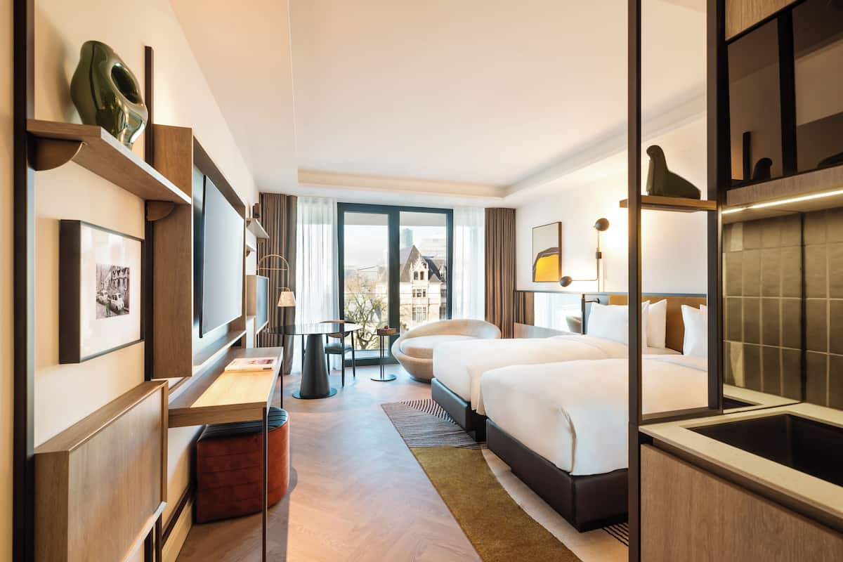 Una habitación de hotel moderna con una cama grande, un escritorio y vistas a la ciudad.