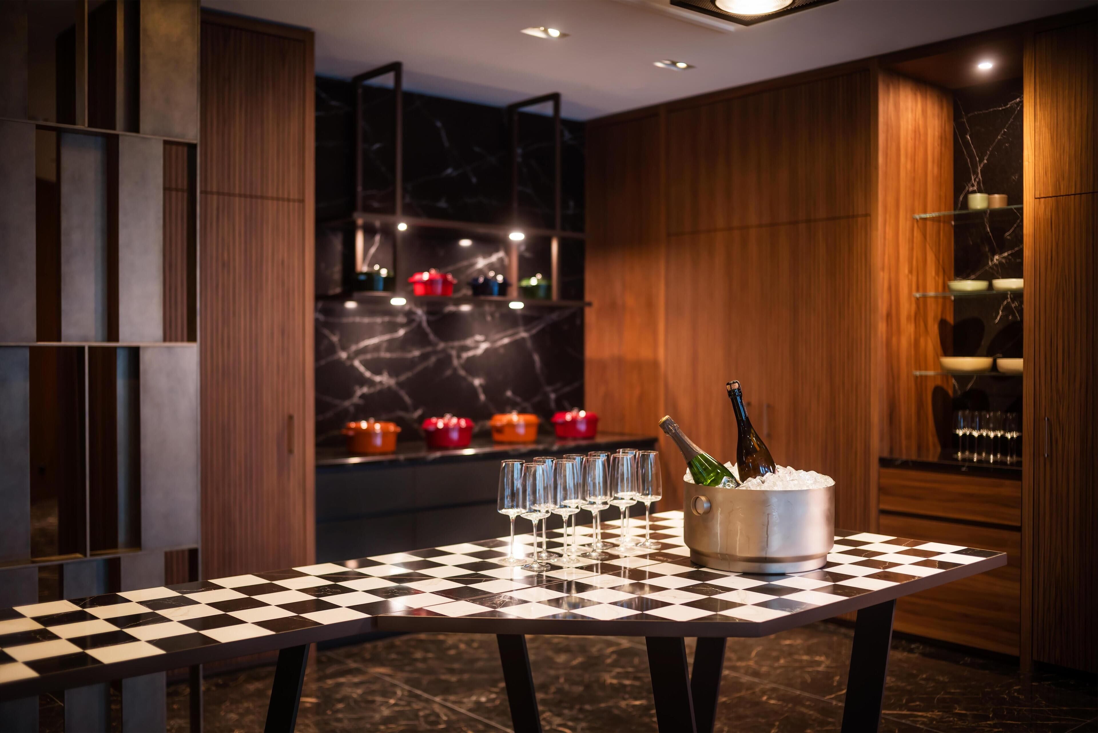 Une table à carreaux, avec des verres et un seau rempli de bouteilles de champagne, dans un intérieur moderne.