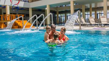 A swimming pool with a family enjoying the water, indoor seating, and a view of the outdoors.