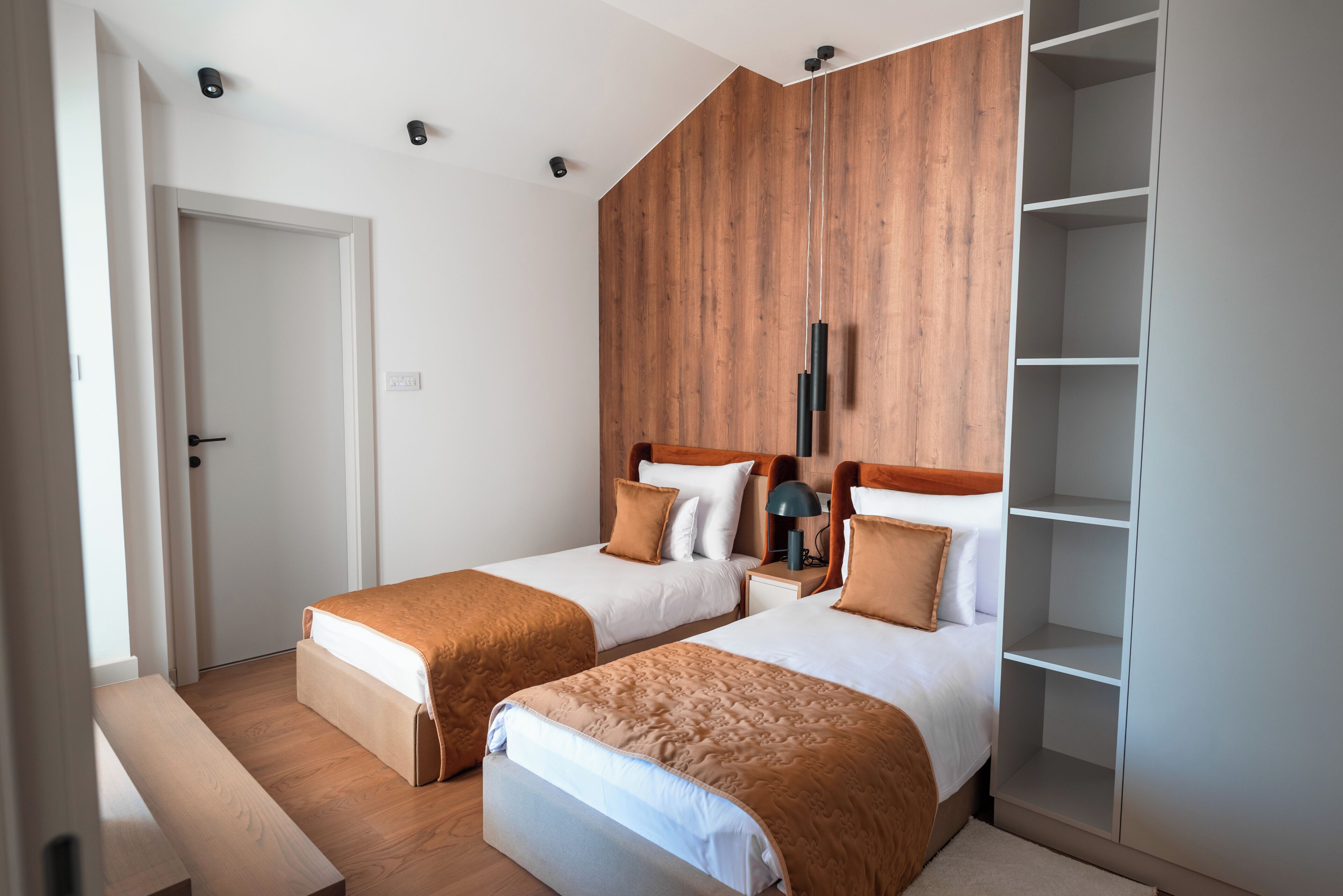 A bedroom with two beds, a wooden wardrobe, and a white door.