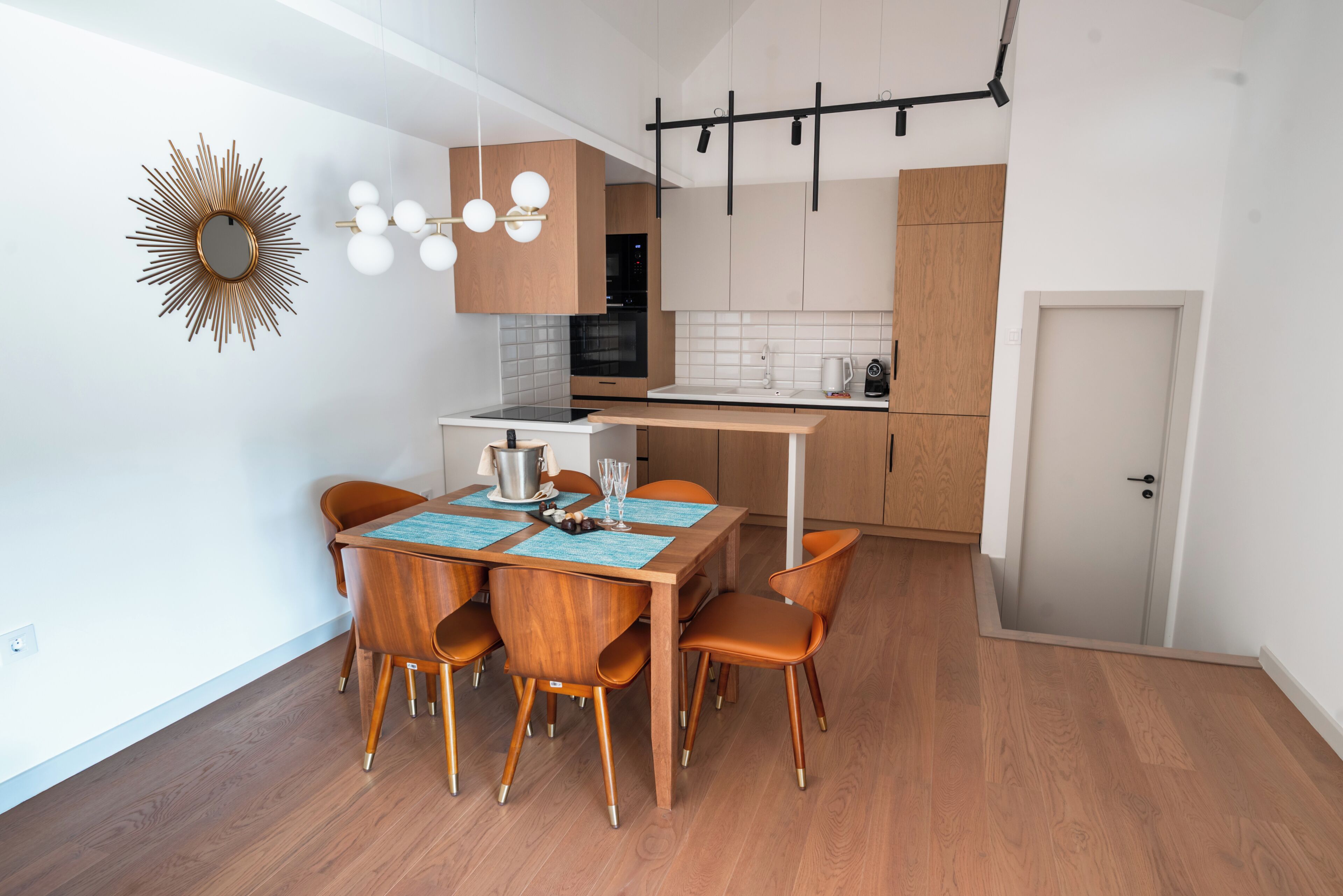 Eine moderne Küche mit Holzschränken, einem Esstisch mit Stühlen und einem Einbauofen.