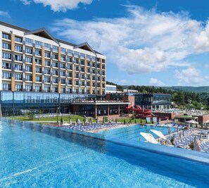 A hotel with a large pool, a water slide, and a mountain backdrop. - Fruške Residences (Vrdnik)