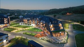 A modern multi-story hotel with a central courtyard, outdoor seating area, and a view of the surrounding landscape.