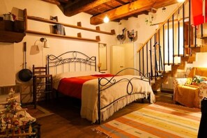 A cozy bedroom with a metal bed frame, a wooden ladder, a red throw blanket, and a striped rug.