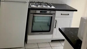 Uma cozinha compacta com geladeira, fogão, forno e janela sobre a pia.