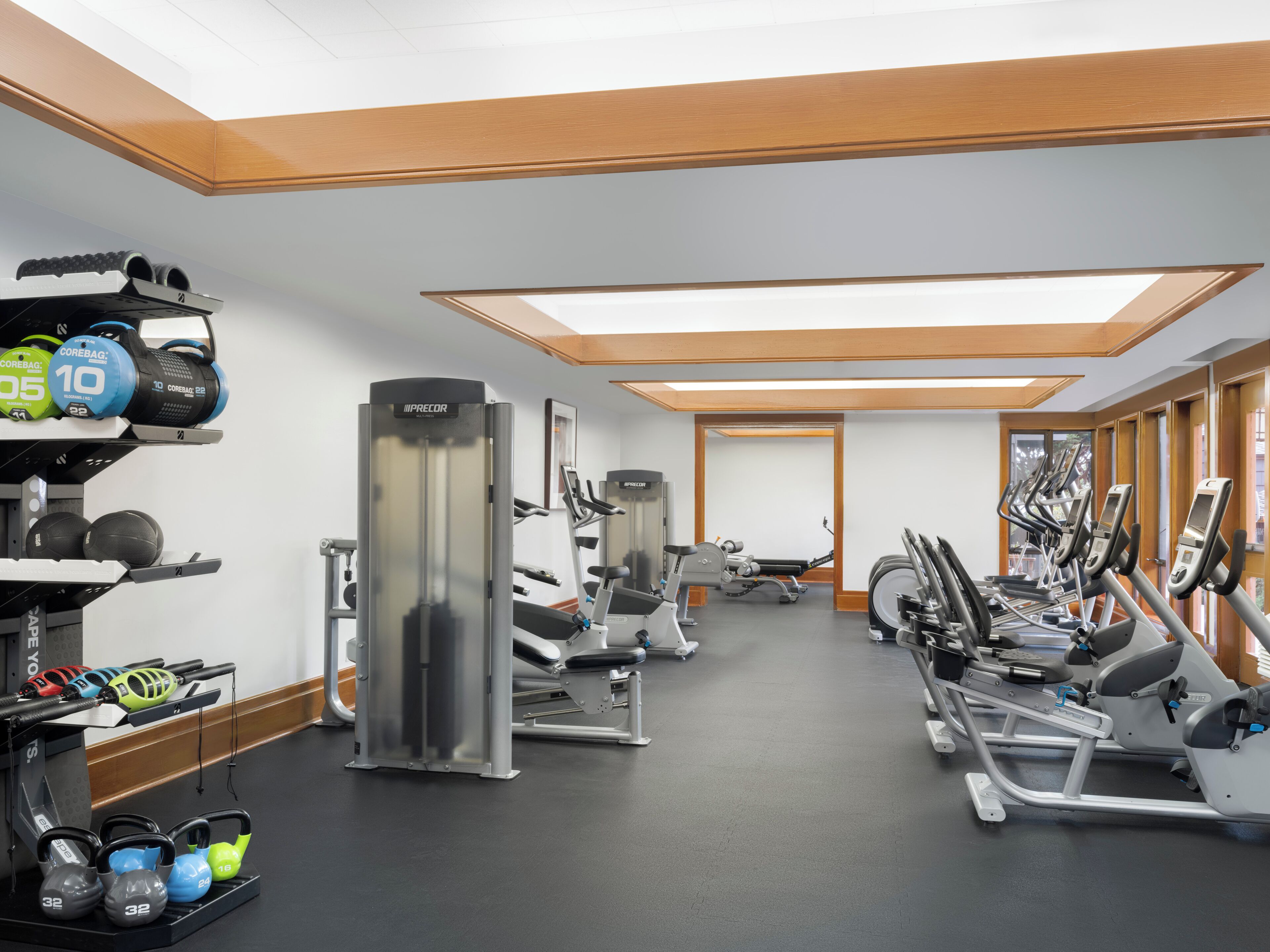 A gym with various exercise equipment, including treadmills, weight machines, and kettlebells.