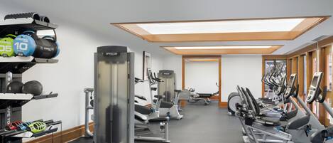 A gym with various exercise equipment, including treadmills, weight machines, and kettlebells.