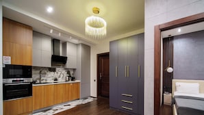 A modern kitchen with wooden cabinets, a built-in oven, and a marble backsplash. - Arch Apart Hotel (Yerevan)
