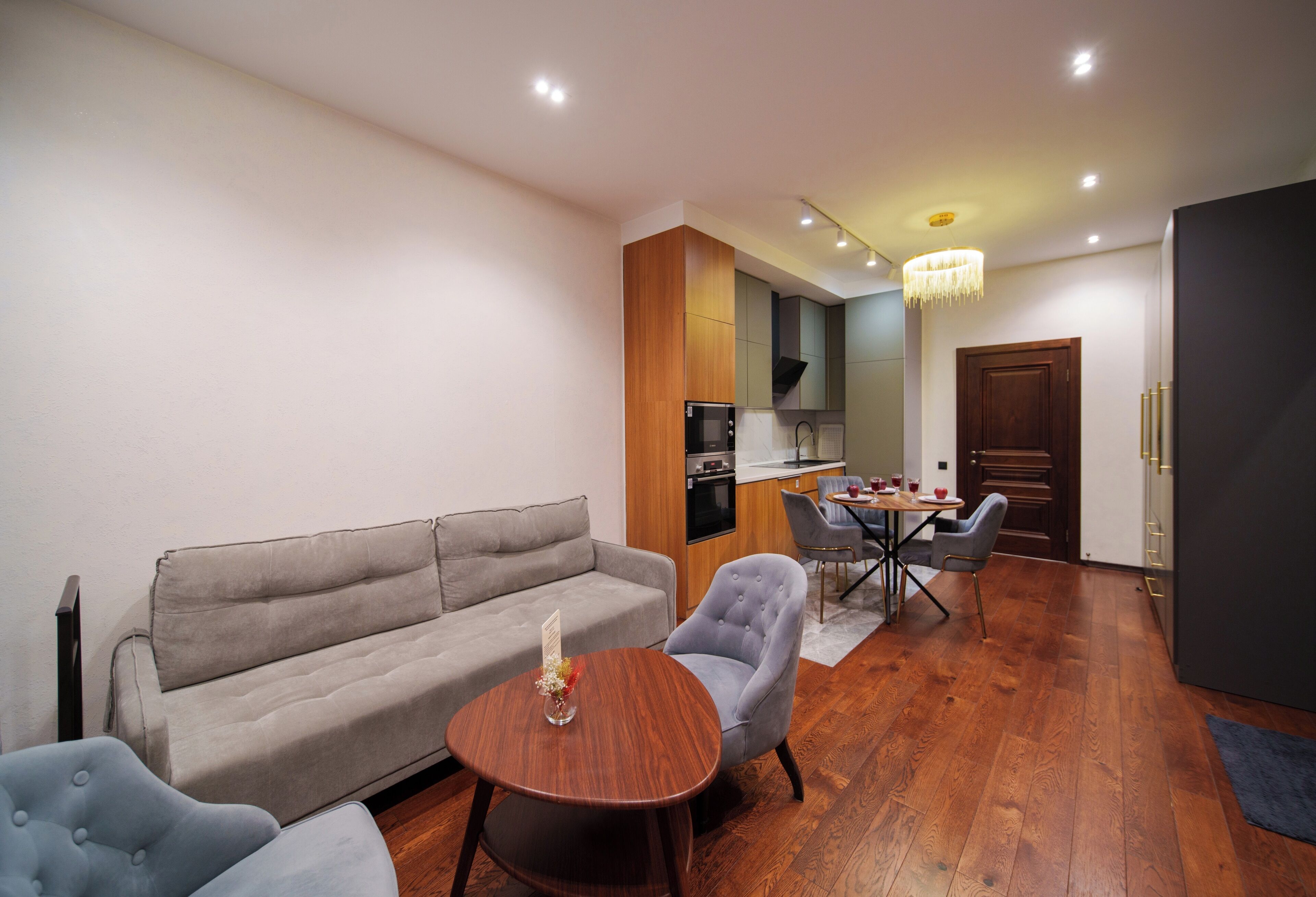 A modern living room with a sofa, armchair, and round table.
